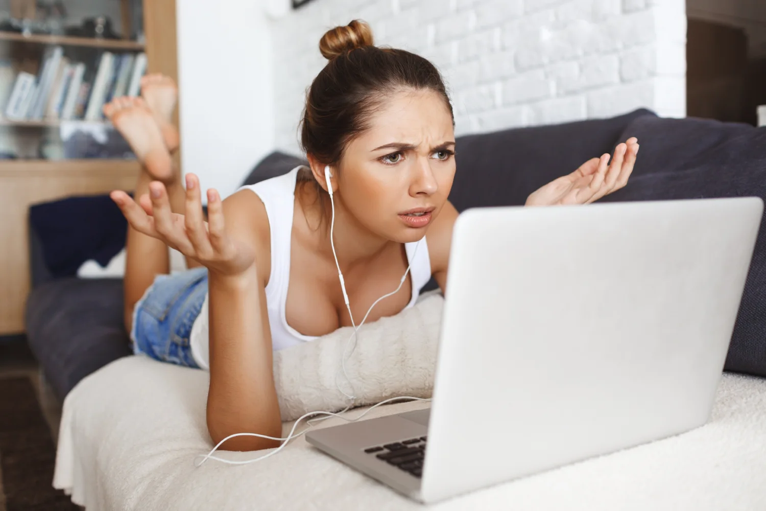Verwirrte junge Frau liegt mit Laptop auf dem Sofa – typische Internetprobleme auf Reisen in Thailand ohne richtige eSIM-Einrichtung.