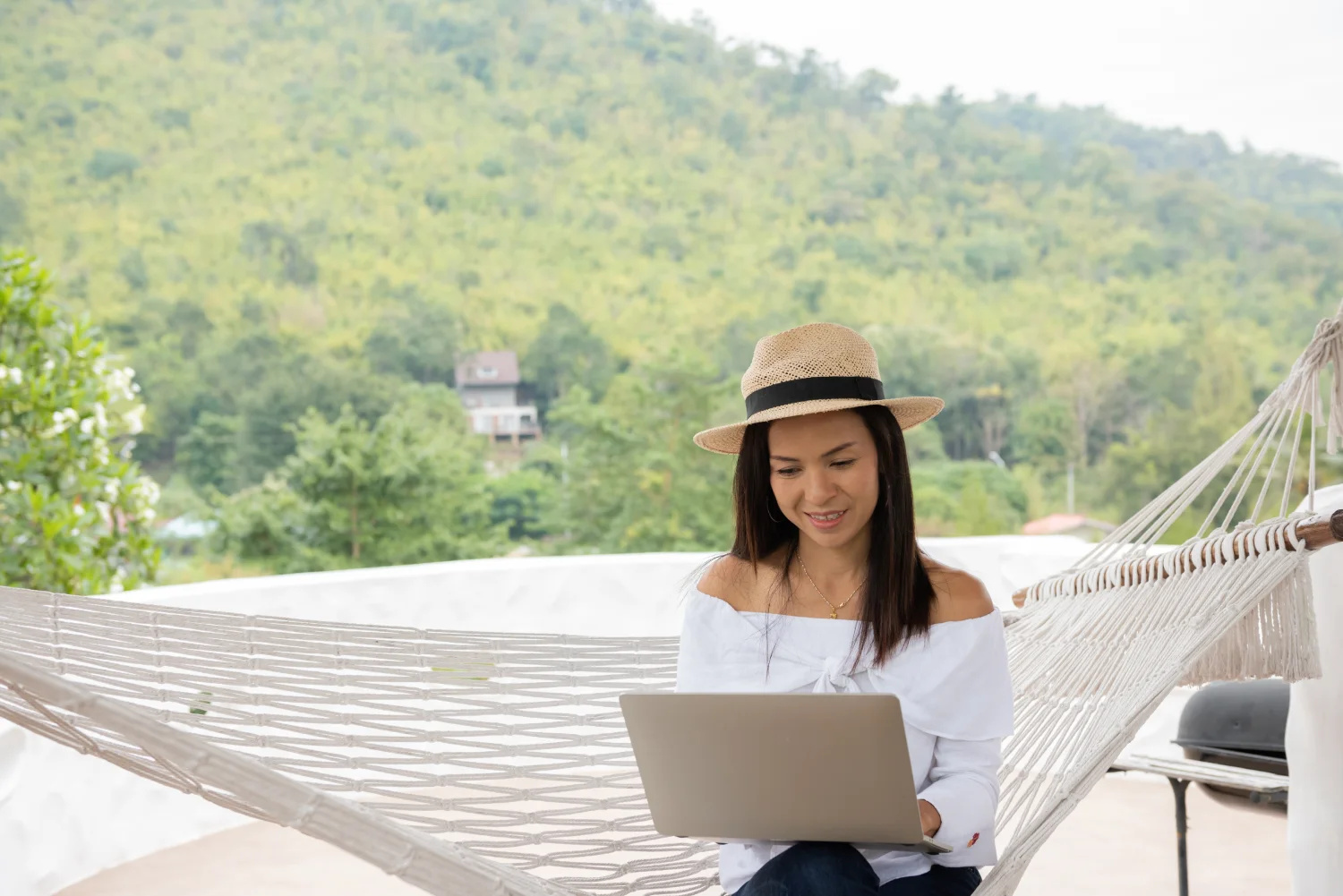 Junge Reisende entspannt mit Laptop in Hängematte am tropischen Strand – dank eSIM Thailand sofort online und startklar für Remote Work.